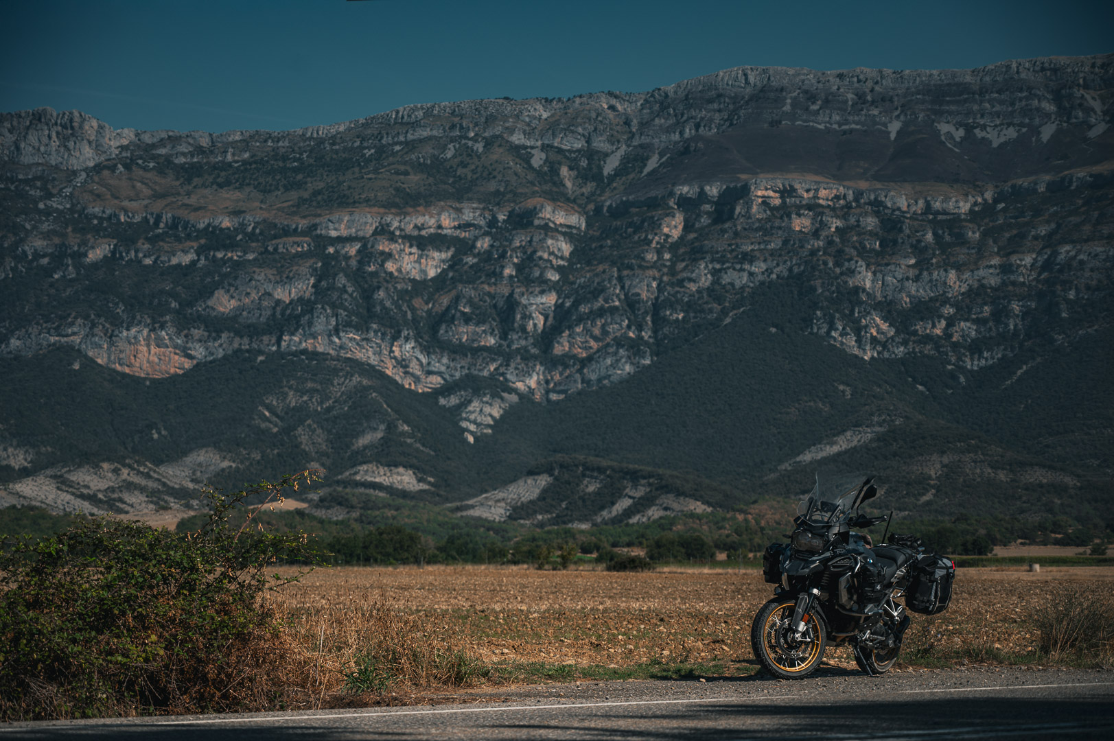 Motorcycle parked beneath a limestone ridge